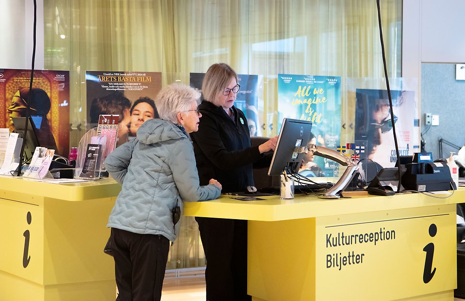 Två personer står vid en informationsdisk.