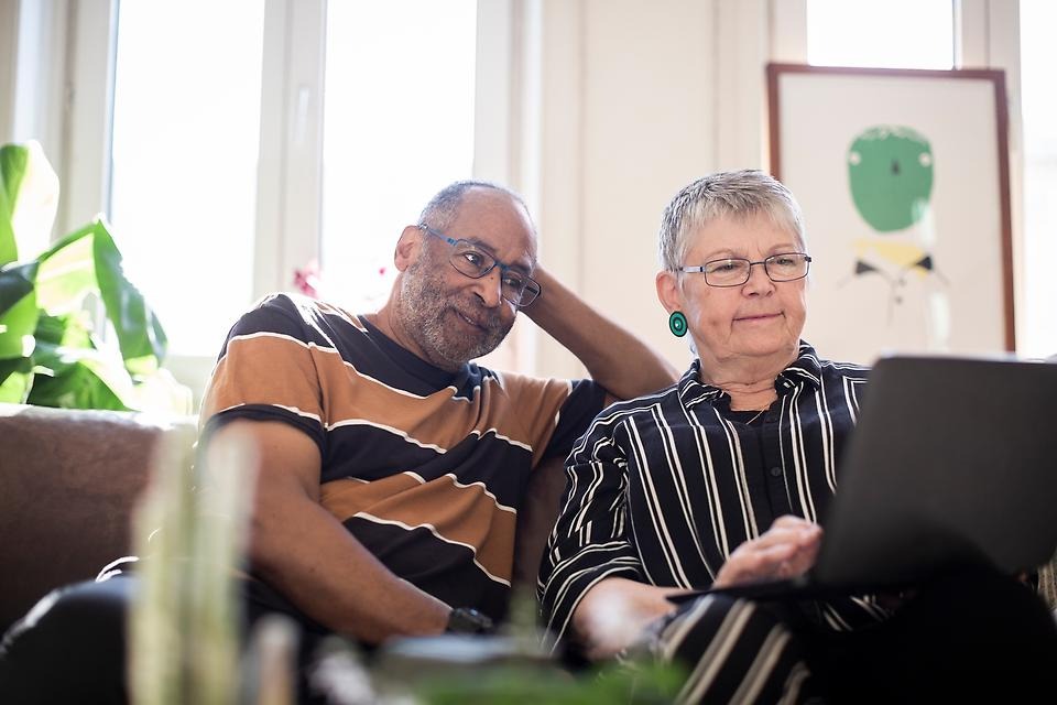 Två personer sitter i en soffa och tittar på en dator