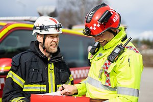 Brandmän diskuterar vid brandbil.